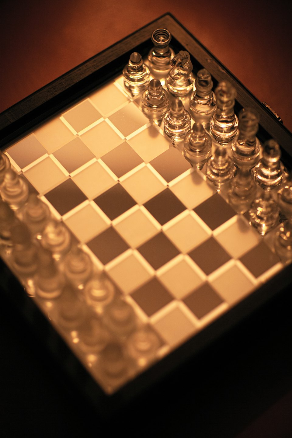 Glass chess pieces set up on a chessboard.