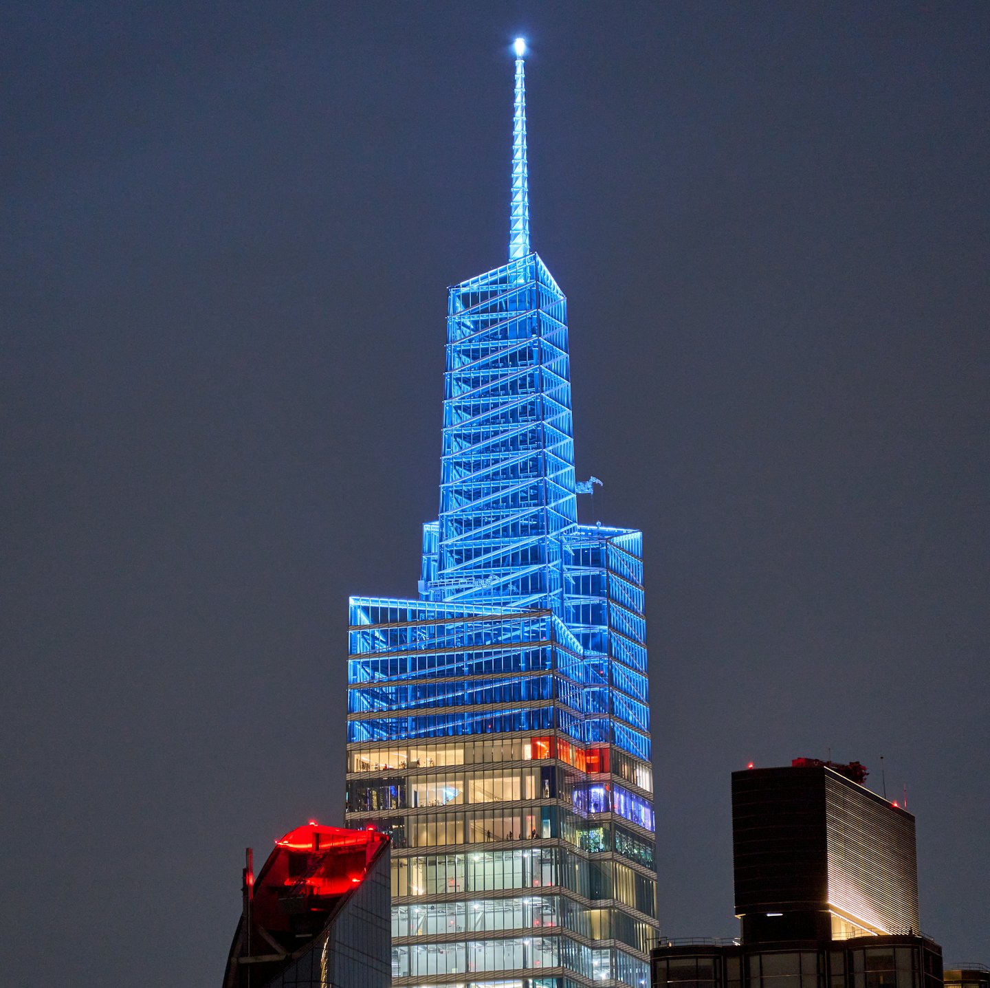 Modern skyscraper with blue glowing lights at night.