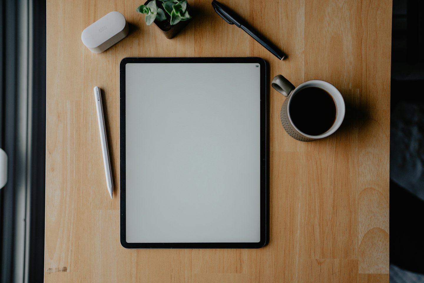 Tablet and office supplies on a wooden desk.